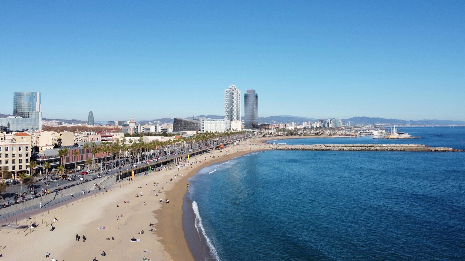 A stunning aerial shot of Barcelona's beach and city skyline on a clear day, capturing the vibrant coast.