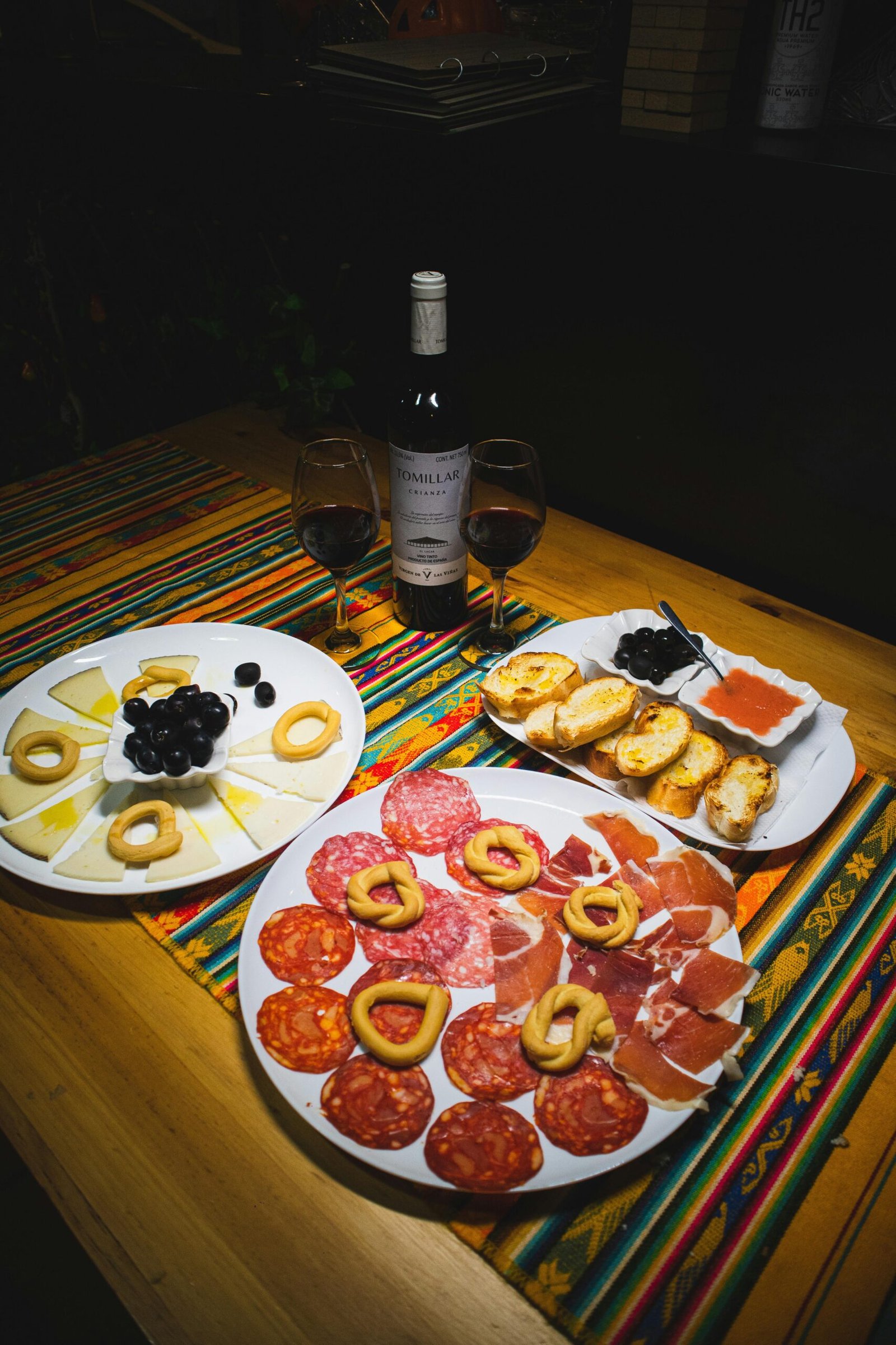 A vibrant array of Spanish tapas with olives, cheese, cured meats, and wine, perfect for a cozy indoor dining experience.